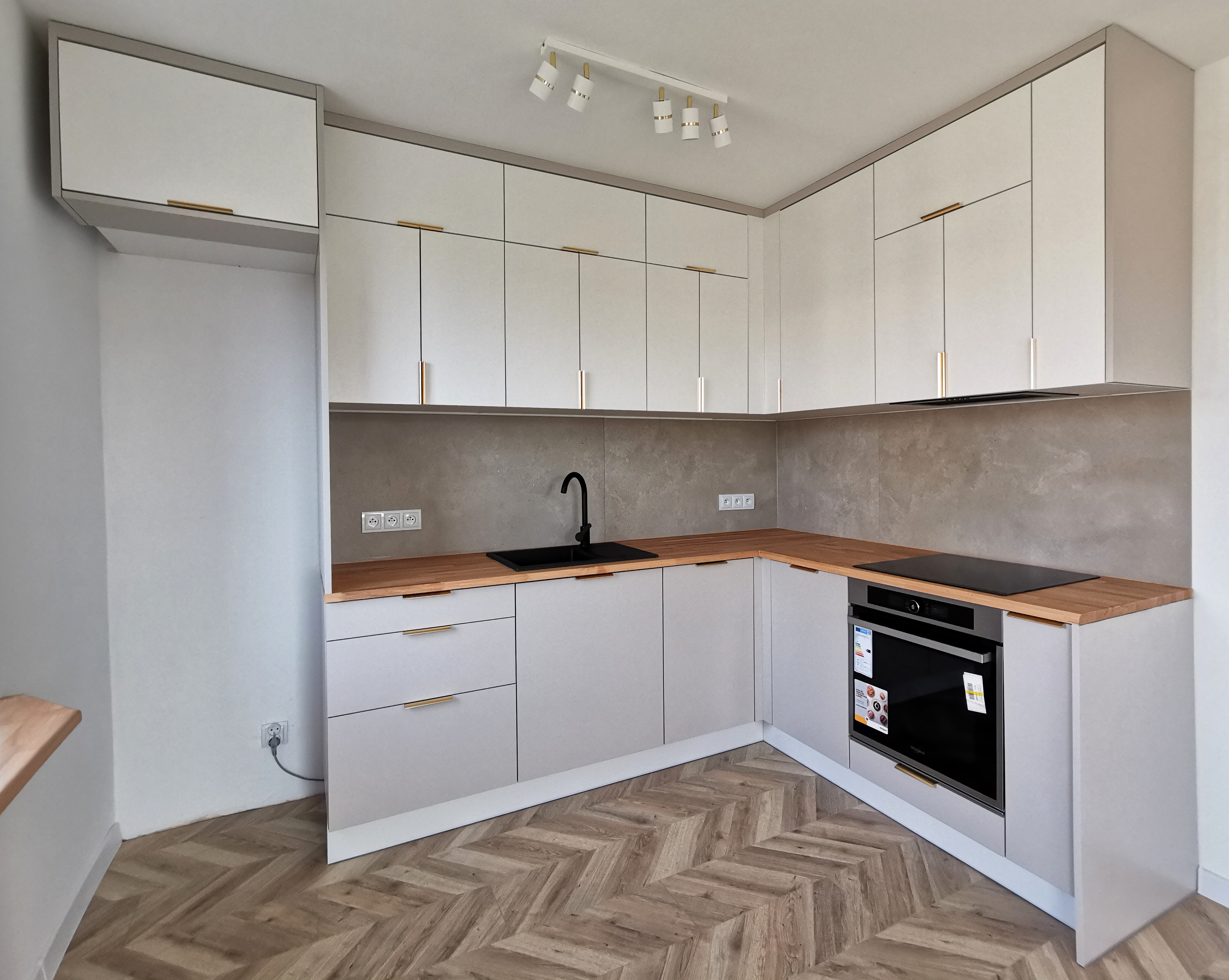 Biała kuchnia z drewnianymi blatami i szarym tłem