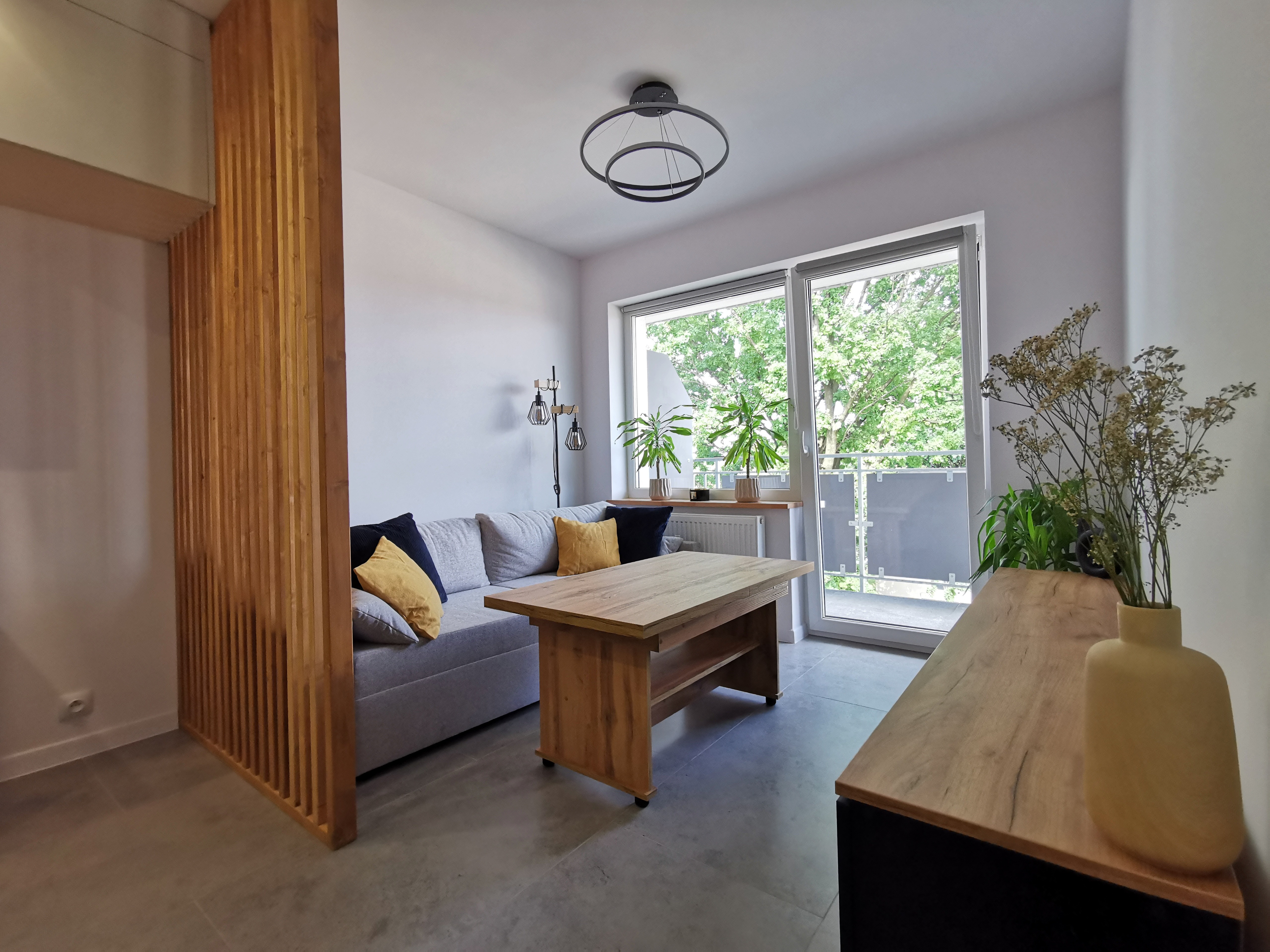 Jasny salon z drewnianymi akcentami i dostępem do balkonu